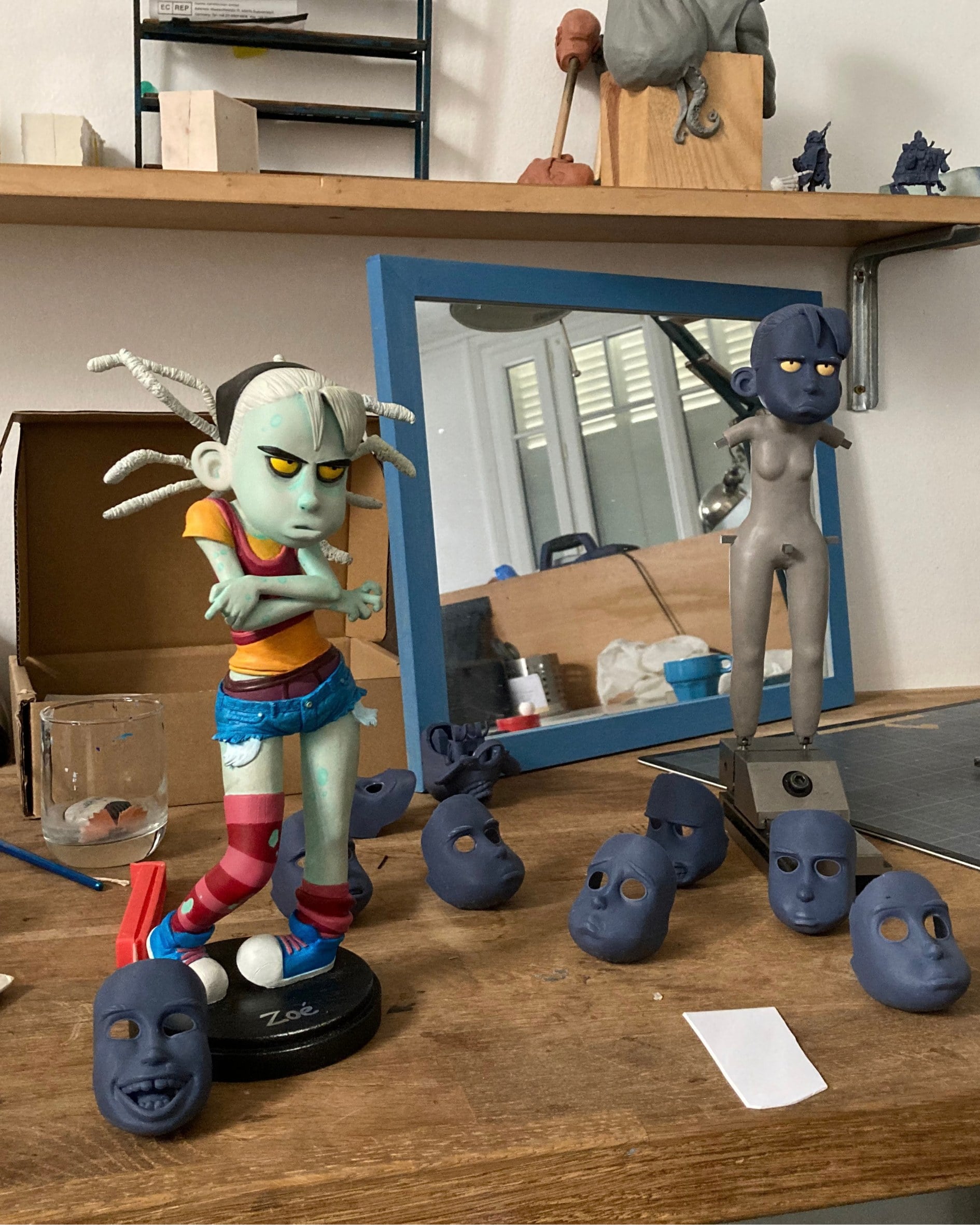 Zoé's puppet on the workbench, surrounded by faces in progress